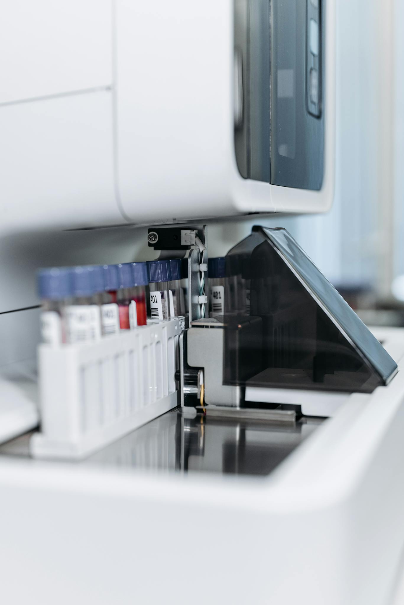 Close-up of an automated laboratory machine handling test tubes for research.