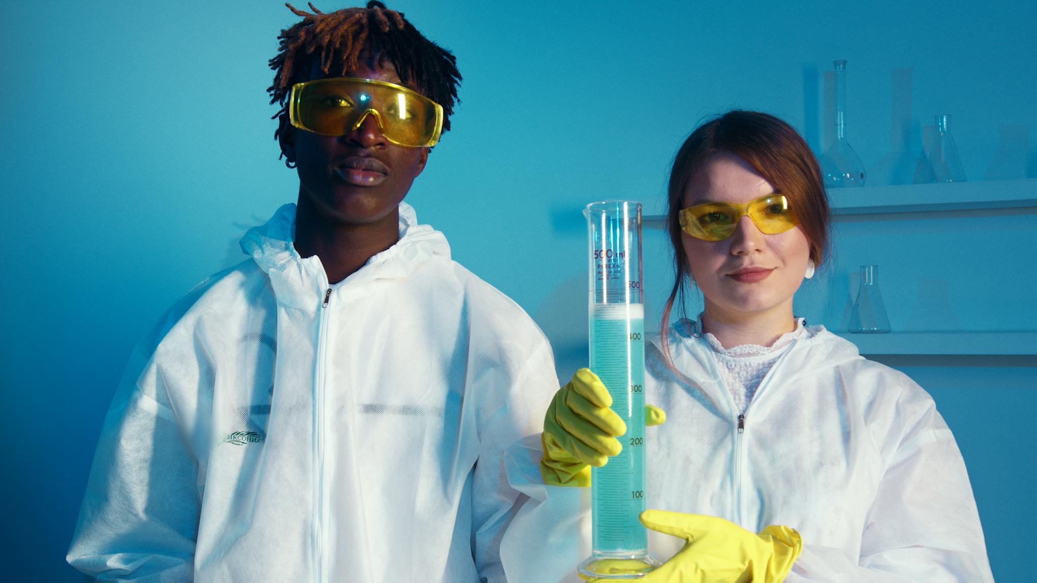 Two scientists in protective gear conducting experiments in a lab setting.